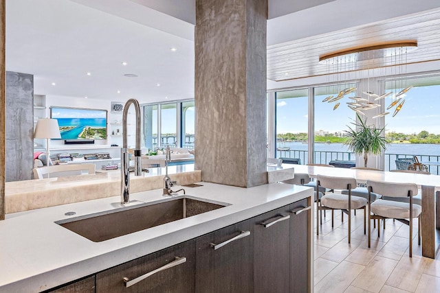 kitchen with dark brown cabinetry, a water view, and sink