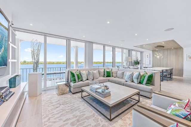 living room with a water view, a healthy amount of sunlight, a notable chandelier, and light wood-type flooring