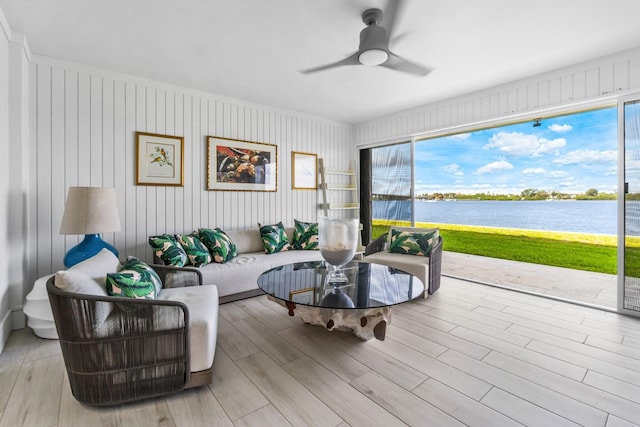 living room with a wealth of natural light, light hardwood / wood-style flooring, a water view, and ceiling fan