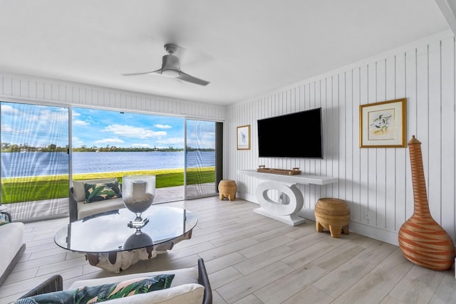 living room with light wood-type flooring, ceiling fan, and wood walls