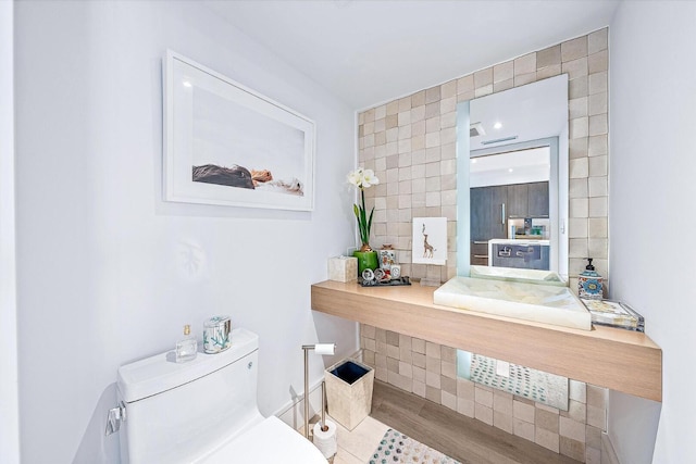 bathroom featuring hardwood / wood-style flooring, toilet, and tile walls