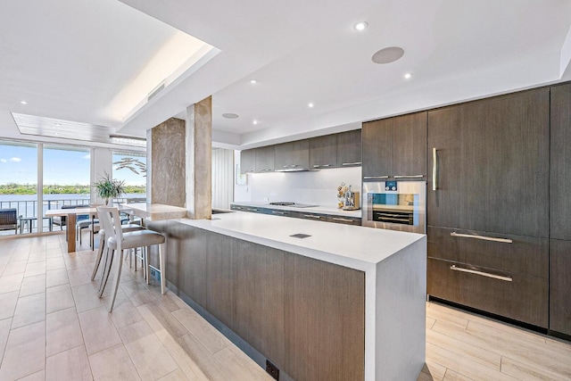 kitchen with stainless steel oven, a center island, light wood-type flooring, and black electric stovetop