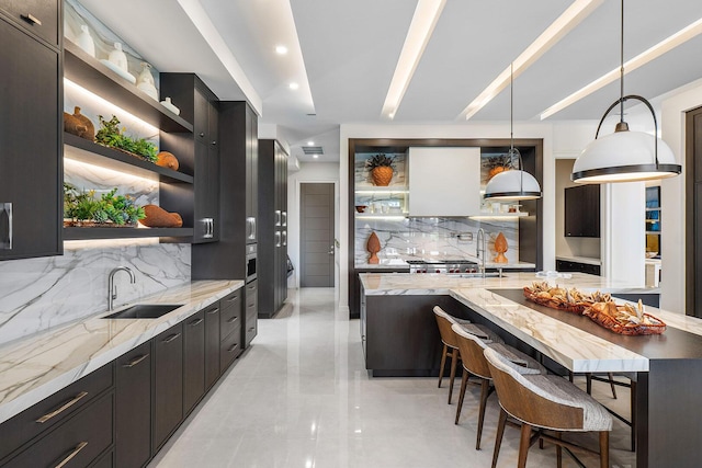 kitchen with a kitchen bar, decorative backsplash, sink, and decorative light fixtures