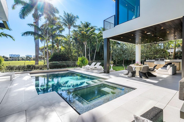 view of pool featuring a patio area, an in ground hot tub, ceiling fan, and an outdoor kitchen