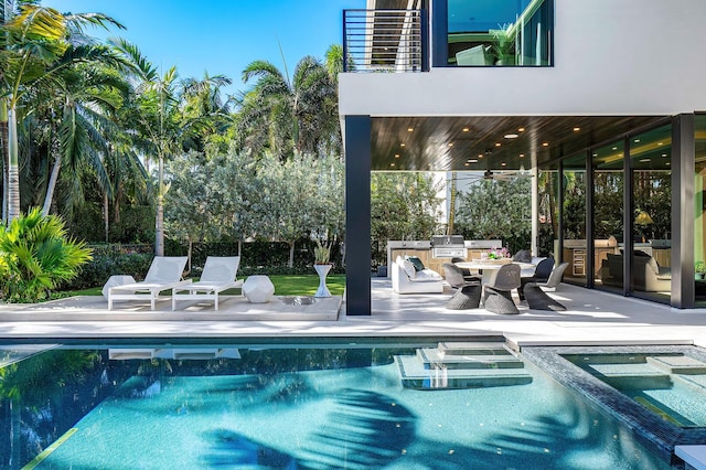 view of pool with an in ground hot tub, an outdoor kitchen, ceiling fan, and a patio area