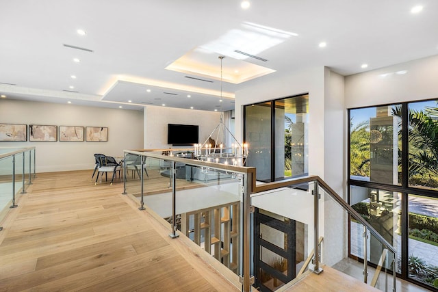 hallway with a raised ceiling and light hardwood / wood-style flooring