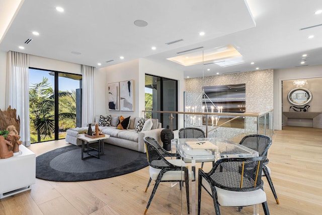 dining room featuring a notable chandelier, light hardwood / wood-style floors, and a tray ceiling