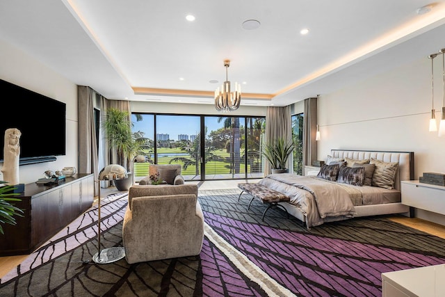 bedroom with a tray ceiling, a chandelier, and hardwood / wood-style flooring