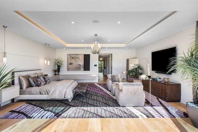 living room featuring a tray ceiling, light hardwood / wood-style flooring, and a notable chandelier