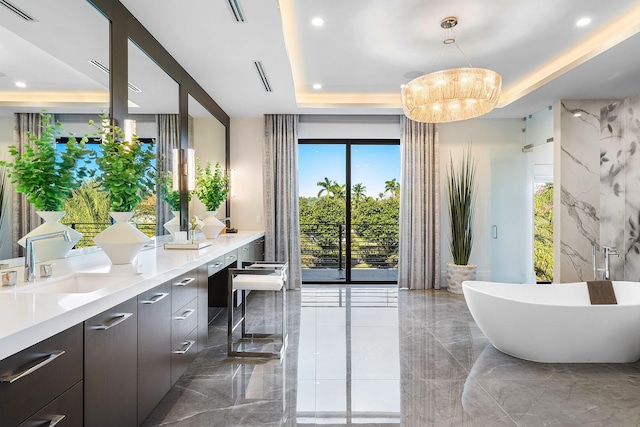 bathroom featuring vanity, a bathtub, a healthy amount of sunlight, and a notable chandelier