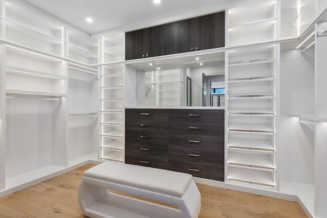 walk in closet with light hardwood / wood-style flooring