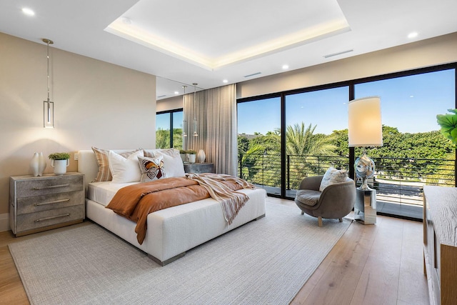 bedroom with a raised ceiling, access to exterior, and hardwood / wood-style flooring