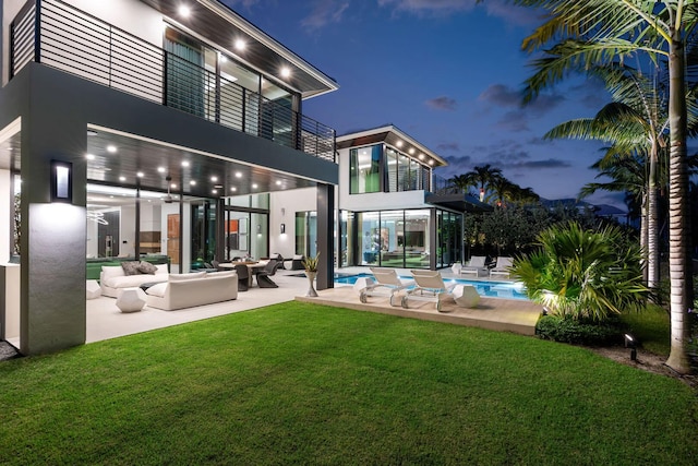 rear view of house featuring a patio area, a balcony, an outdoor hangout area, and a yard