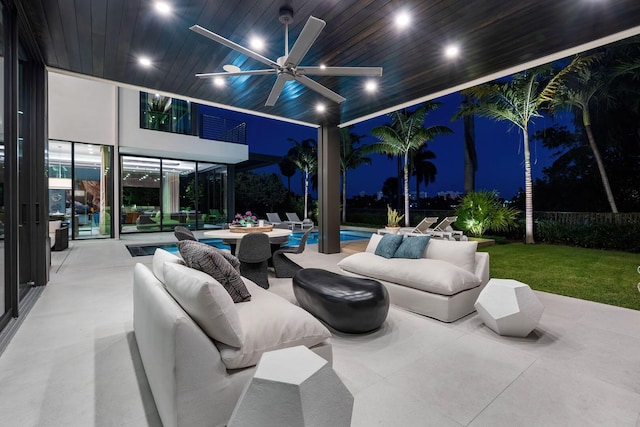 patio at night featuring an outdoor hangout area, a balcony, and ceiling fan