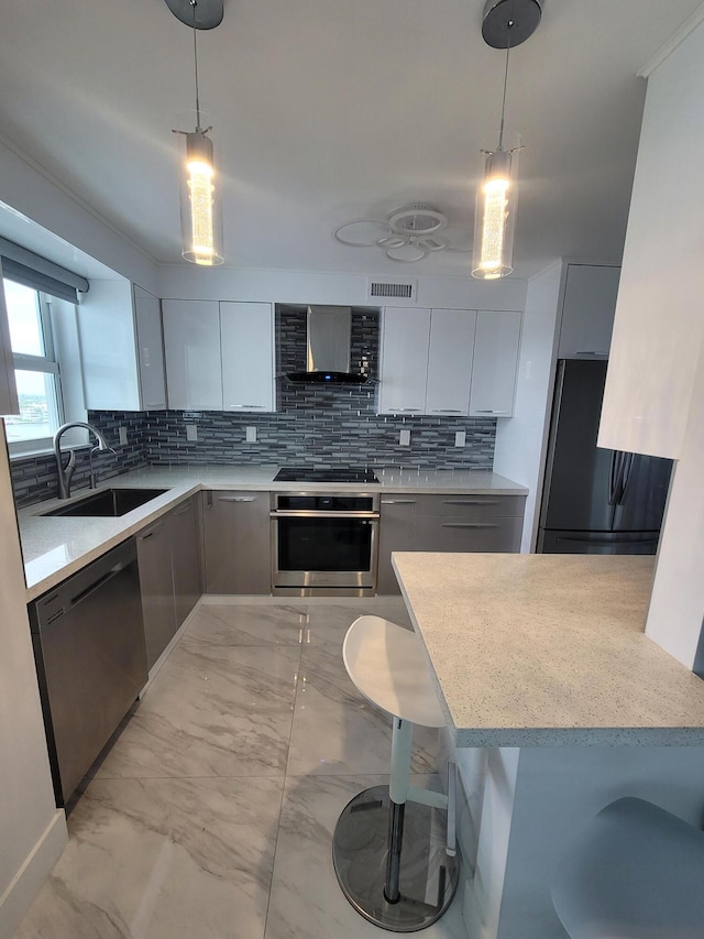 kitchen featuring hanging light fixtures, sink, appliances with stainless steel finishes, and a kitchen bar