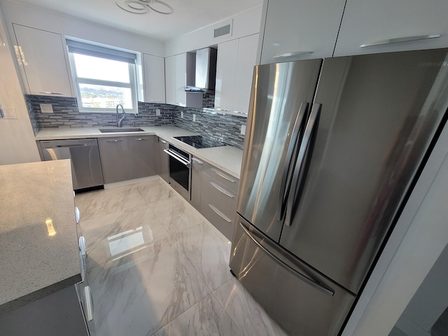 kitchen with visible vents, modern cabinets, a sink, appliances with stainless steel finishes, and wall chimney range hood