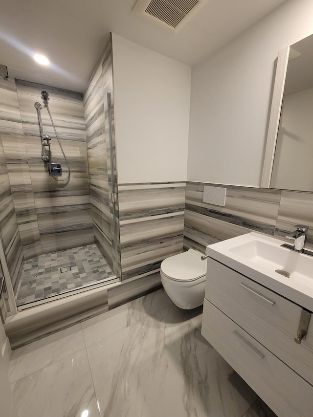 bathroom featuring a tile shower, vanity, and toilet