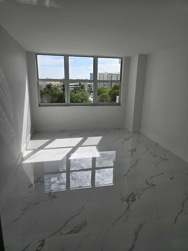 spare room featuring marble finish floor and a view of city