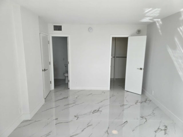 unfurnished bedroom with visible vents, marble finish floor, a walk in closet, and baseboards