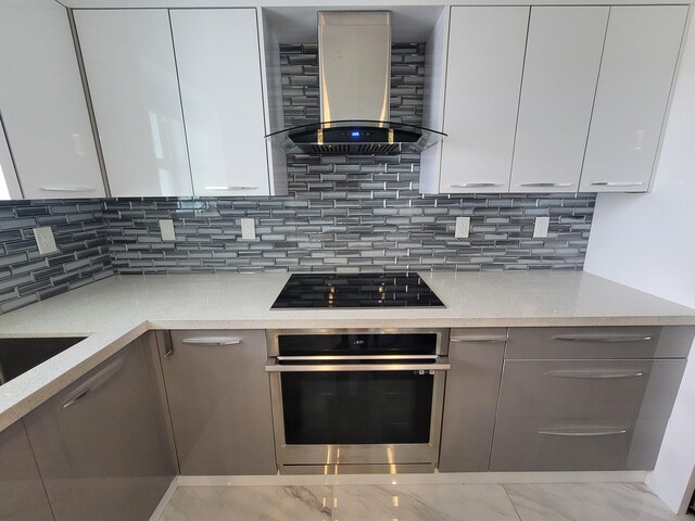 kitchen featuring wall chimney exhaust hood, sink, tasteful backsplash, light stone counters, and stainless steel appliances