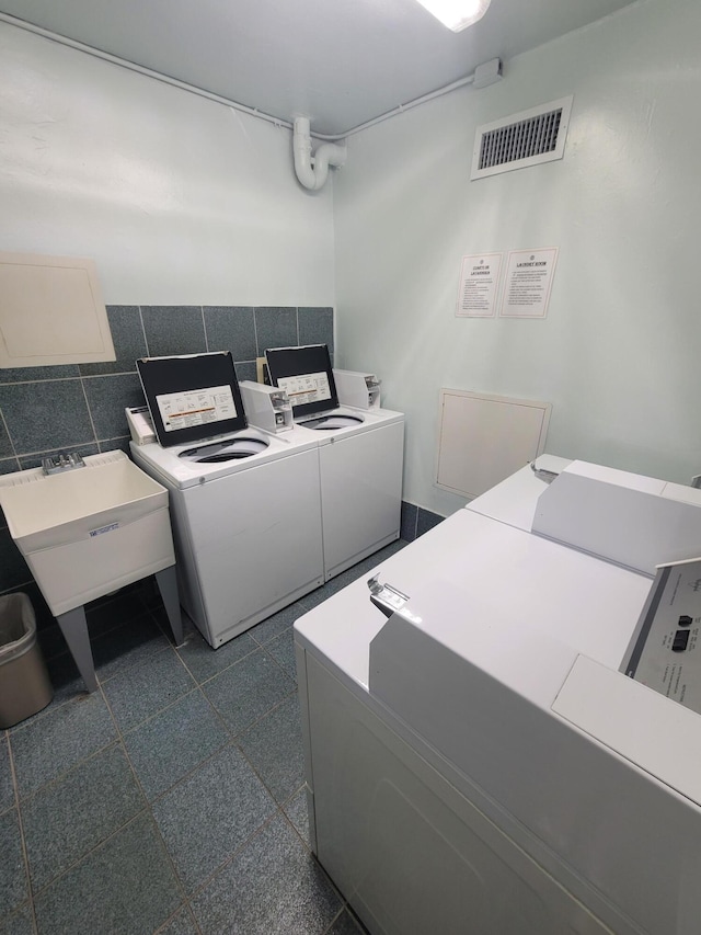 washroom with washer and dryer, sink, and tile walls