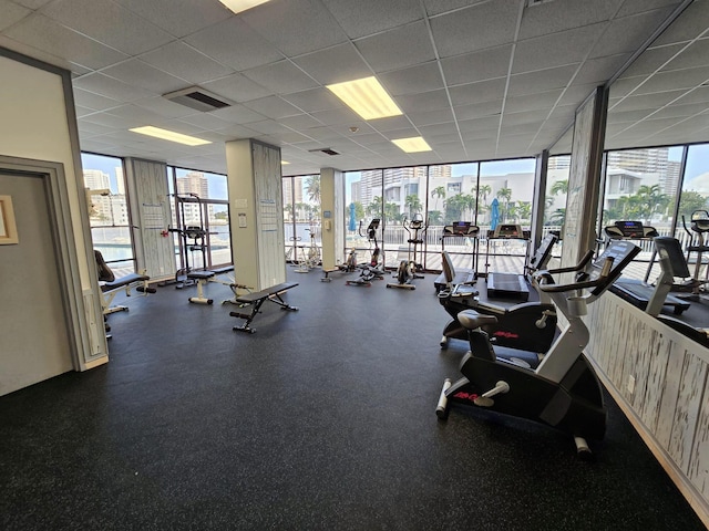 gym with visible vents, a wall of windows, and a drop ceiling