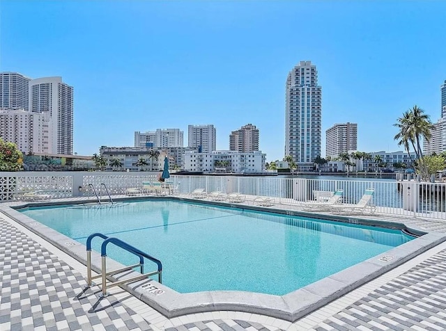 community pool featuring a view of city and fence