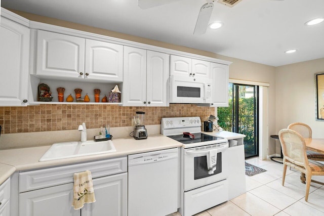 kitchen with white appliances, backsplash, white cabinetry, and sink