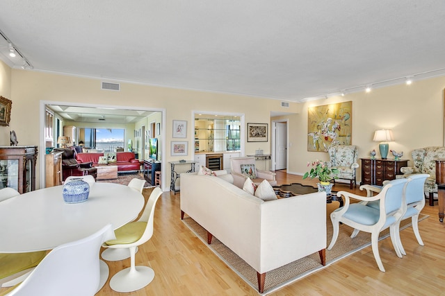 living room with light wood-type flooring, rail lighting, and beverage cooler