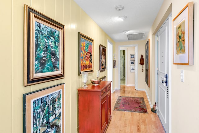 hallway with a textured ceiling and light wood-type flooring