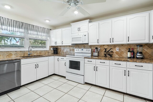 kitchen featuring backsplash, white appliances, sink, dark stone countertops, and white cabinets