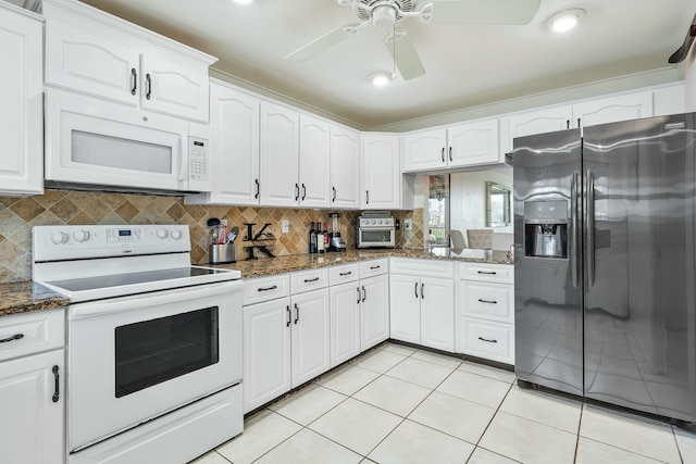 kitchen with white cabinetry, dark stone countertops, white appliances, and light tile patterned floors