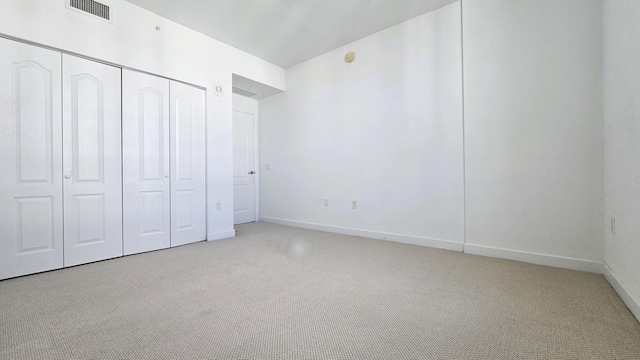 unfurnished bedroom featuring a closet and light colored carpet