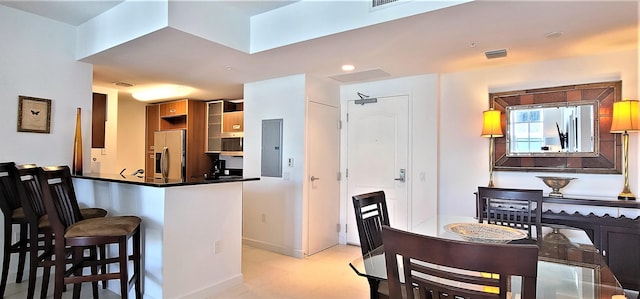 kitchen with a kitchen bar, kitchen peninsula, stainless steel fridge with ice dispenser, and electric panel