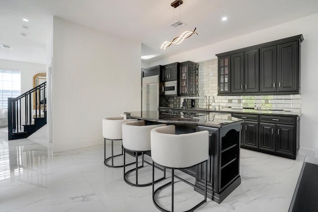 kitchen with a kitchen breakfast bar, tasteful backsplash, sink, pendant lighting, and a kitchen island