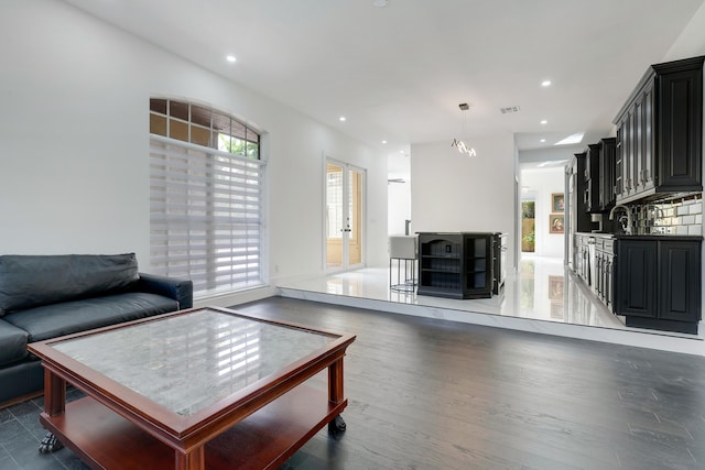 living room featuring sink, dark hardwood / wood-style floors, and a notable chandelier