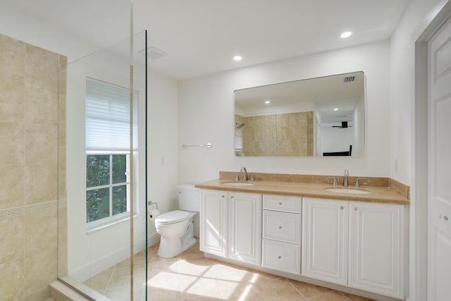 bathroom with tile patterned flooring, vanity, toilet, and a tile shower