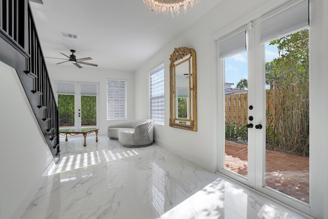 sunroom featuring french doors and ceiling fan with notable chandelier