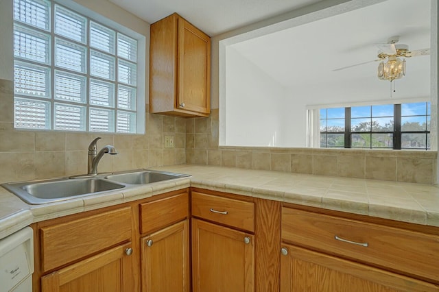 kitchen featuring ceiling fan, tile counters, tasteful backsplash, dishwasher, and sink