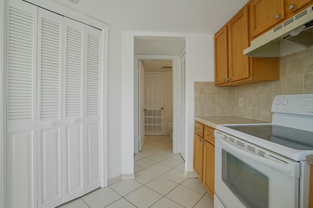 kitchen featuring light tile patterned floors, decorative backsplash, and white electric stove