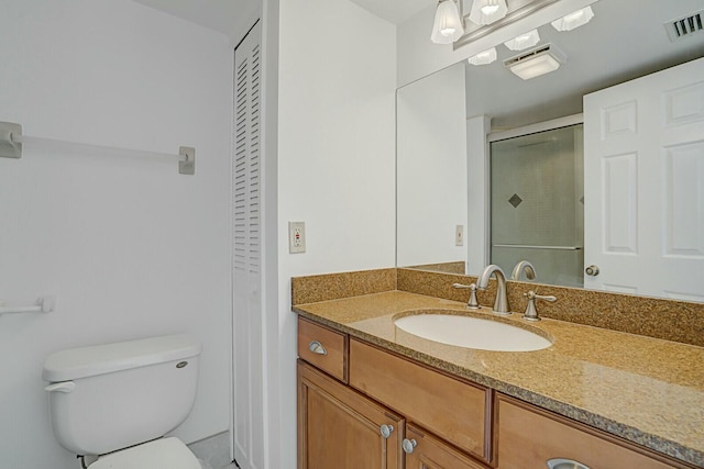 bathroom featuring toilet, a shower with shower door, and vanity