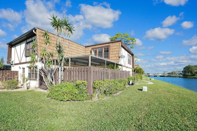 view of side of home featuring a yard and a water view