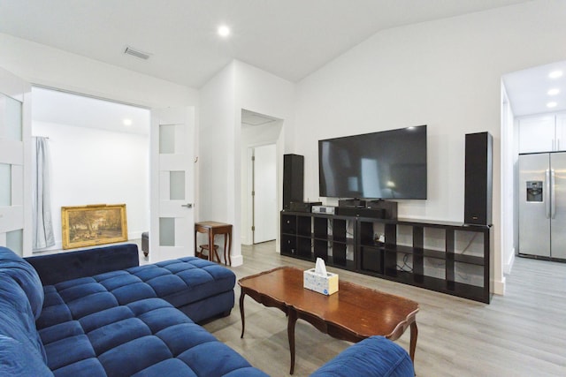 living room featuring light wood-type flooring and vaulted ceiling