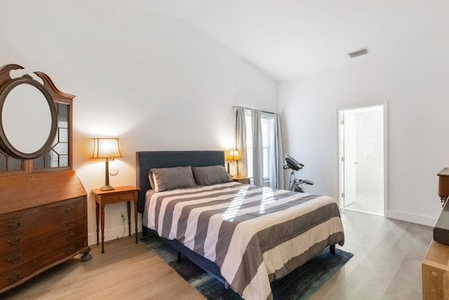 bedroom featuring connected bathroom, light hardwood / wood-style floors, and lofted ceiling