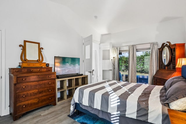 bedroom with access to exterior, light wood-type flooring, and vaulted ceiling