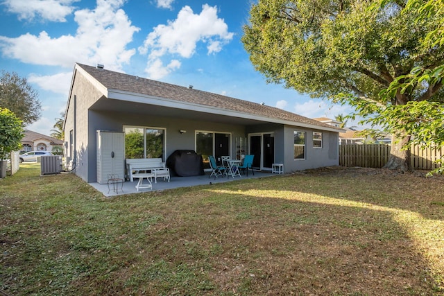 rear view of property with a lawn, a patio area, and central AC unit