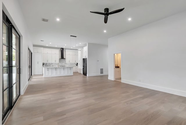 unfurnished living room with light wood-type flooring and ceiling fan