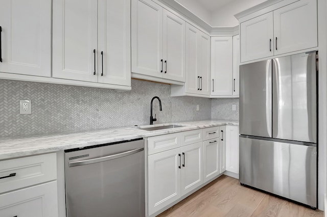 kitchen featuring white cabinets, light hardwood / wood-style floors, sink, and appliances with stainless steel finishes