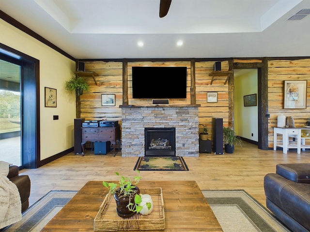 living room with ceiling fan, wood-type flooring, a fireplace, and wooden walls