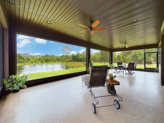 sunroom with ceiling fan and a water view